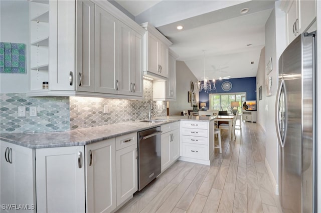 kitchen featuring white cabinets, appliances with stainless steel finishes, kitchen peninsula, and lofted ceiling