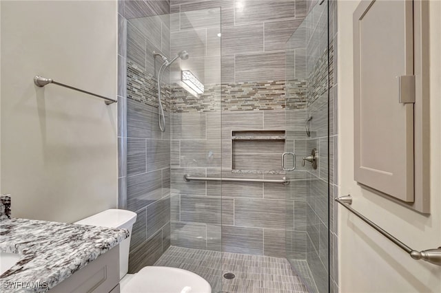 bathroom with a shower with door, vanity, and toilet