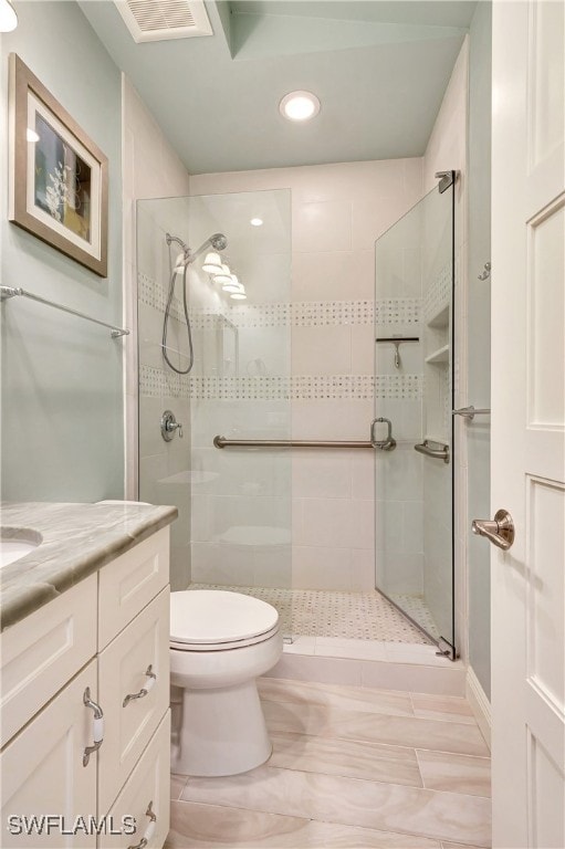 bathroom with tiled shower, vanity, and toilet