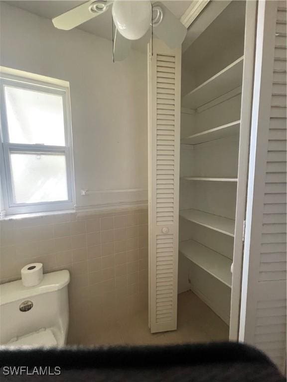 bathroom featuring tile walls and ceiling fan