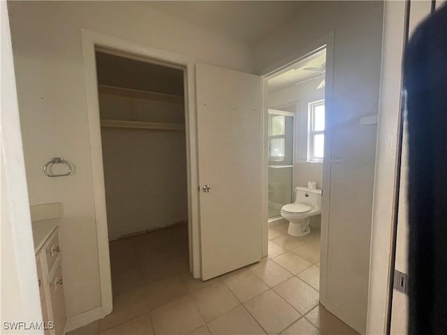 bathroom featuring tile patterned flooring, a shower with door, and toilet