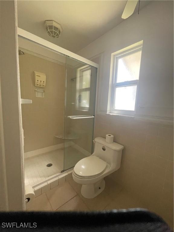 bathroom featuring tile walls, tile patterned flooring, an enclosed shower, ceiling fan, and toilet