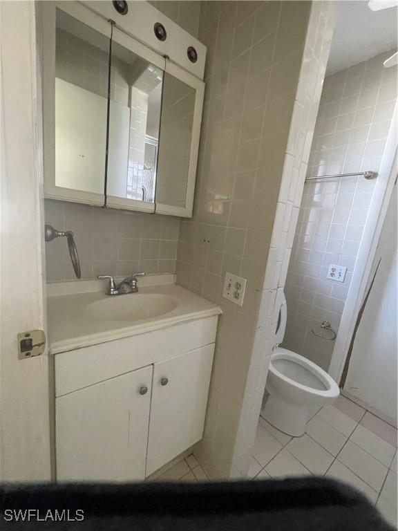 bathroom with decorative backsplash, tile patterned floors, tile walls, and vanity