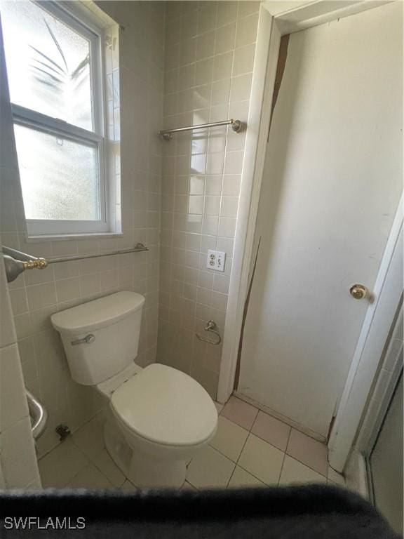 bathroom with tile walls, tile patterned floors, and toilet