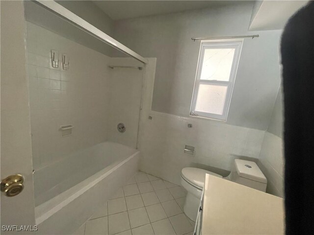 bathroom with tile patterned flooring, bathing tub / shower combination, tile walls, and toilet