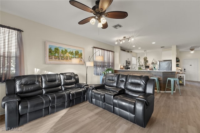 living room with ceiling fan and light wood-type flooring