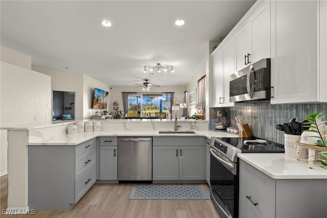 kitchen featuring gray cabinetry, sink, stainless steel appliances, light hardwood / wood-style flooring, and kitchen peninsula