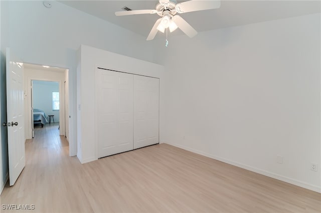 unfurnished bedroom with light wood-type flooring, a closet, and ceiling fan