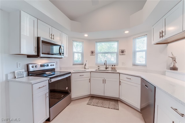 kitchen featuring light stone countertops, appliances with stainless steel finishes, sink, white cabinetry, and lofted ceiling