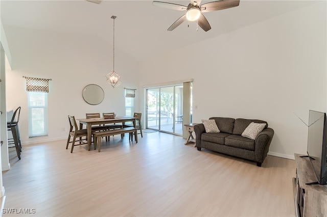 dining area with a high ceiling, light hardwood / wood-style floors, ceiling fan, and a healthy amount of sunlight