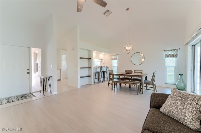 dining area with ceiling fan, a high ceiling, and light hardwood / wood-style flooring