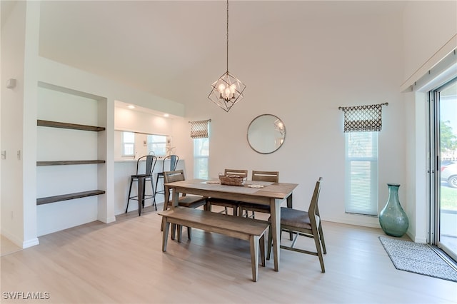 dining space with a healthy amount of sunlight, light wood-type flooring, and a high ceiling