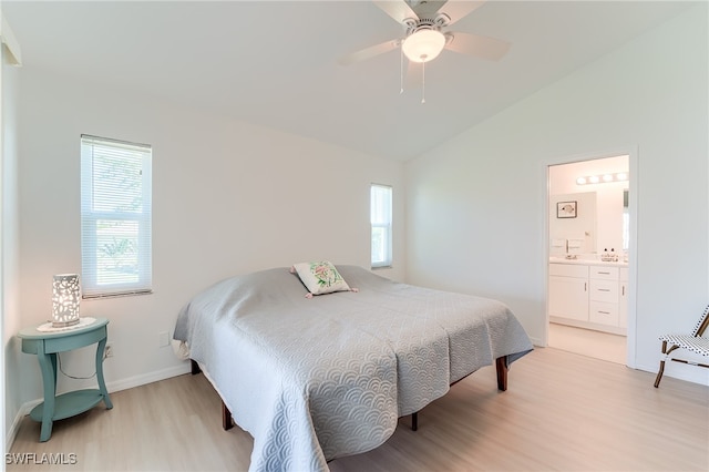 bedroom featuring ceiling fan, lofted ceiling, connected bathroom, and light hardwood / wood-style flooring