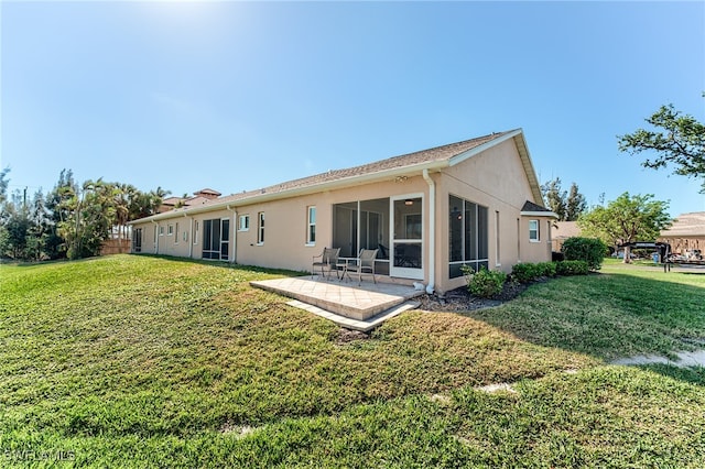 rear view of house with a lawn, a sunroom, and a patio area