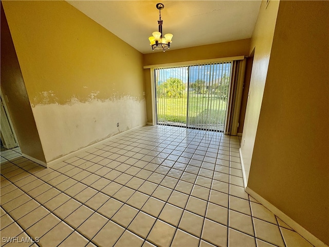 tiled spare room with a notable chandelier