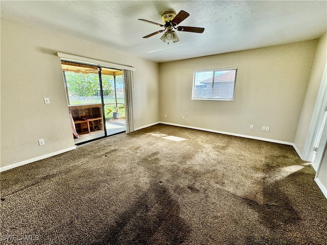 carpeted spare room featuring a textured ceiling, a wealth of natural light, and ceiling fan