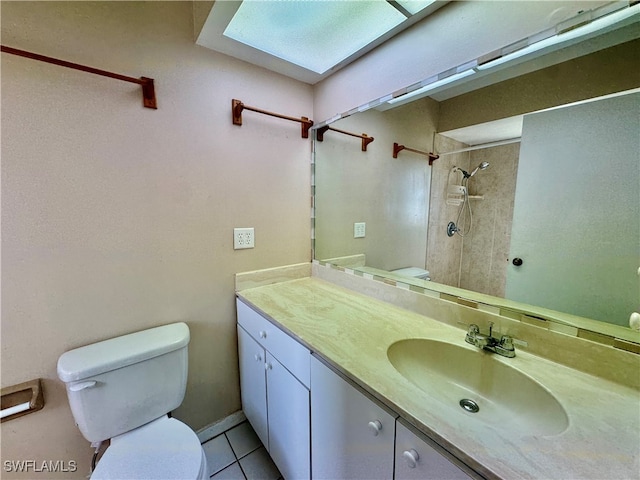 bathroom featuring a tile shower, a skylight, tile patterned floors, toilet, and vanity