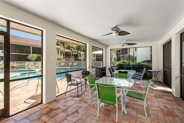 sunroom with ceiling fan and a swimming pool