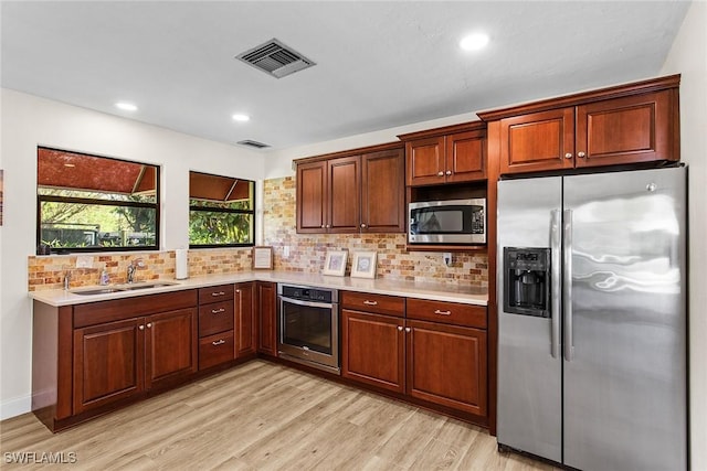 kitchen featuring appliances with stainless steel finishes, light hardwood / wood-style floors, tasteful backsplash, and sink