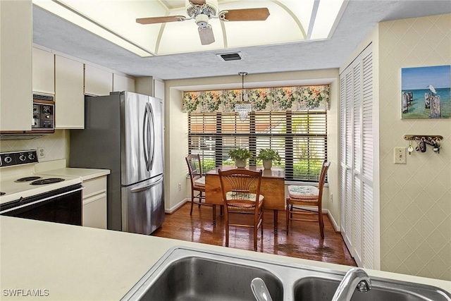 kitchen featuring pendant lighting, white cabinetry, black microwave, stainless steel fridge, and range with electric cooktop