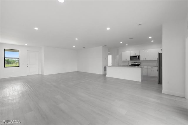 unfurnished living room with light hardwood / wood-style flooring and sink