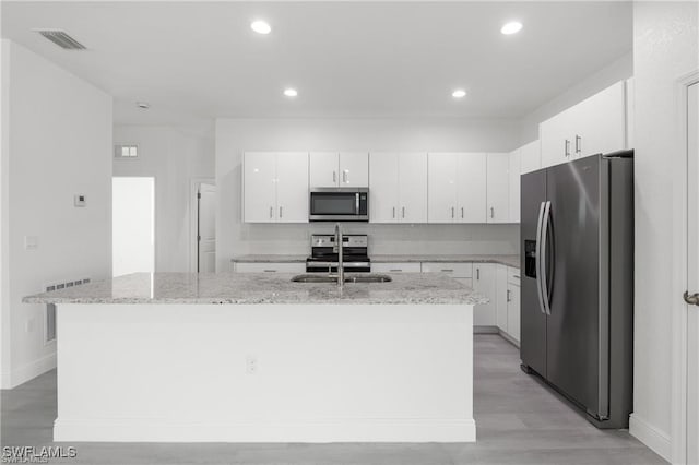 kitchen featuring white cabinets, sink, stainless steel appliances, and an island with sink