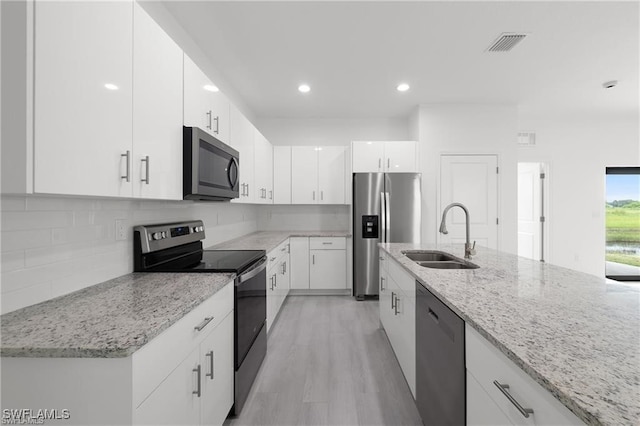 kitchen with stainless steel appliances, white cabinetry, light hardwood / wood-style floors, and sink