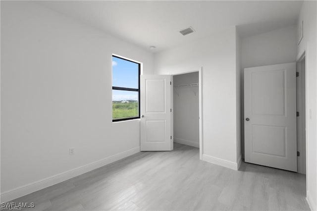 unfurnished bedroom with light wood-type flooring and a closet