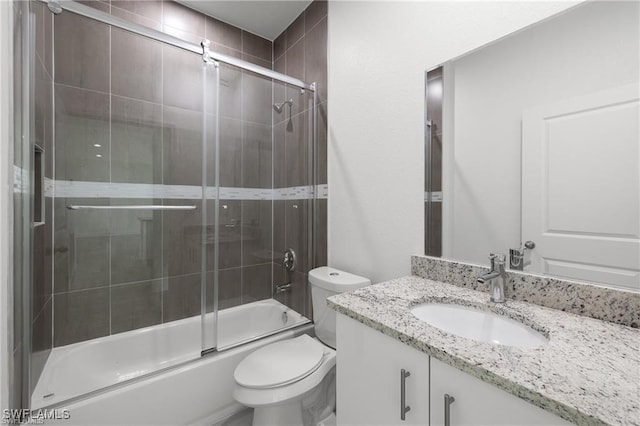 full bathroom featuring vanity, toilet, and shower / bath combination with glass door