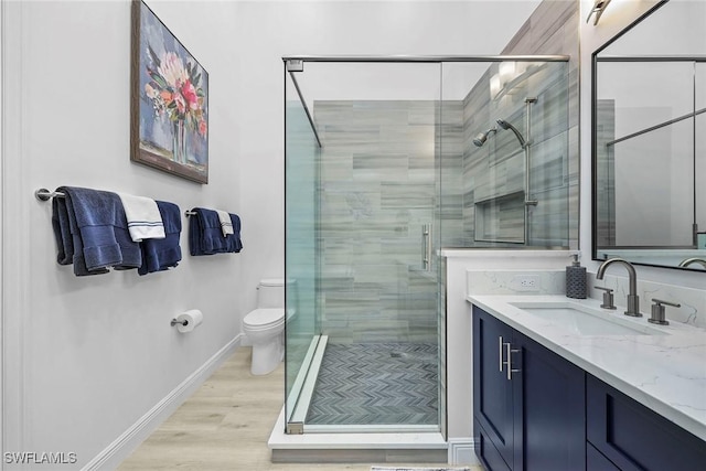 bathroom with vanity, hardwood / wood-style flooring, a shower with door, and toilet