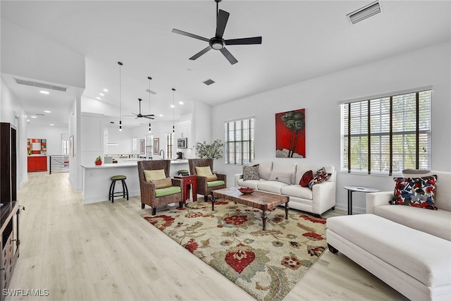 living room with lofted ceiling, light hardwood / wood-style flooring, and ceiling fan