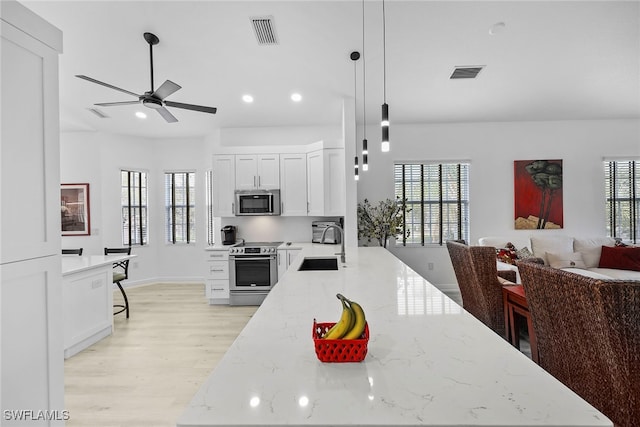 kitchen with sink, white cabinetry, hanging light fixtures, stainless steel appliances, and light stone countertops