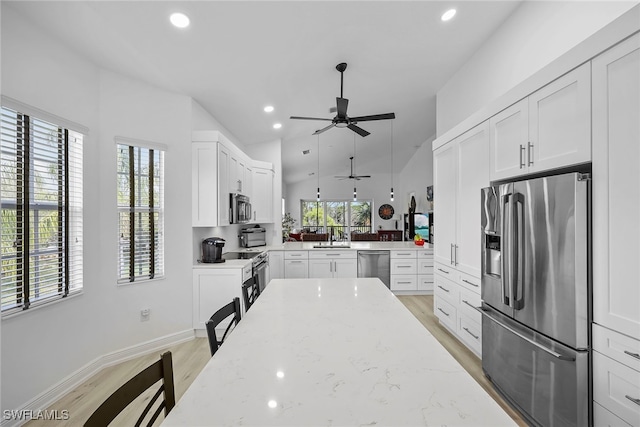 kitchen featuring appliances with stainless steel finishes, light stone countertops, light wood-type flooring, and white cabinets