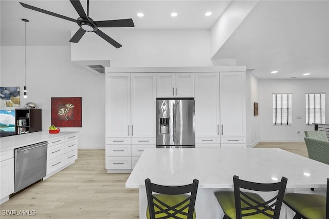 kitchen featuring decorative light fixtures, a breakfast bar area, white cabinets, a center island, and stainless steel appliances