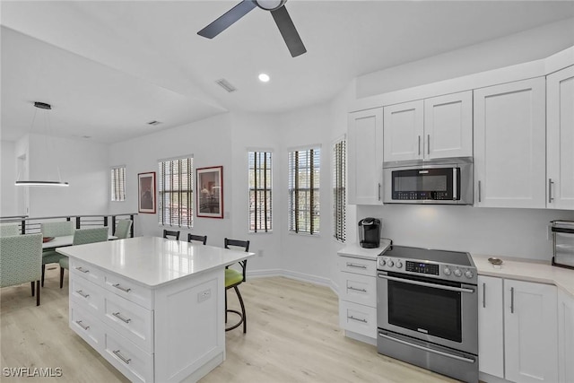 kitchen featuring stainless steel appliances, decorative light fixtures, light hardwood / wood-style flooring, and white cabinets