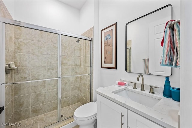 bathroom featuring vanity, toilet, and a shower with door