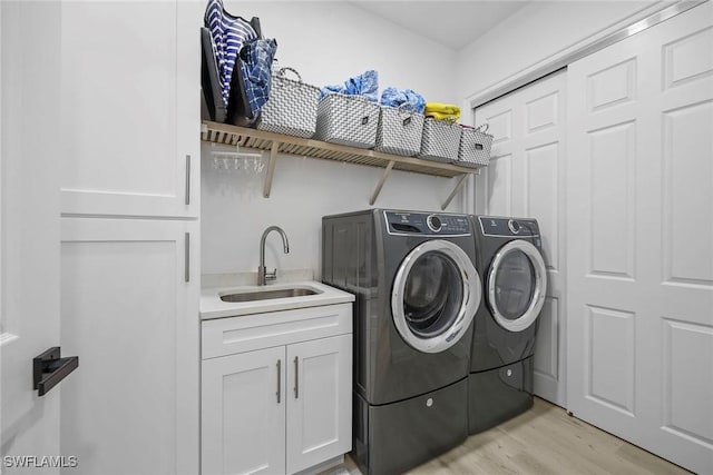 laundry area with separate washer and dryer, sink, light hardwood / wood-style flooring, and cabinets