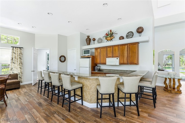 kitchen with white appliances, dark hardwood / wood-style floors, and a breakfast bar