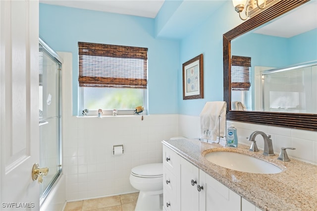 full bathroom with vanity, shower / bath combination with glass door, tile patterned floors, toilet, and tile walls