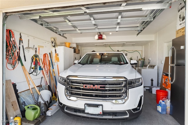 garage featuring washer and dryer, stainless steel refrigerator, and a garage door opener