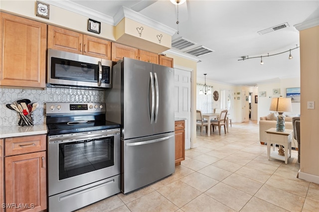 kitchen featuring an inviting chandelier, crown molding, appliances with stainless steel finishes, tasteful backsplash, and light tile patterned flooring