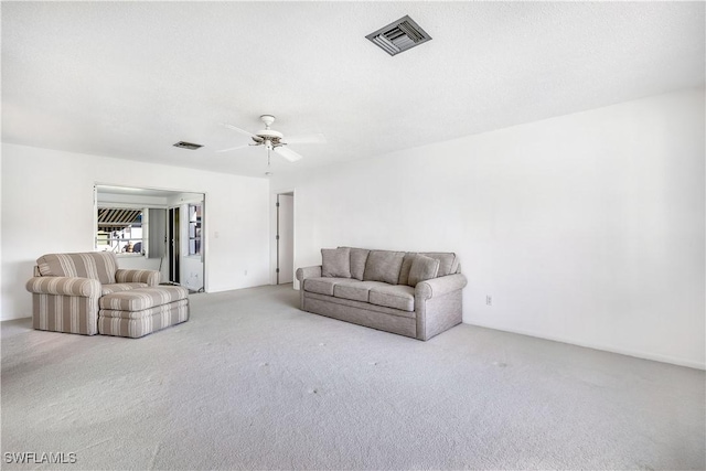 carpeted living room featuring a textured ceiling and ceiling fan