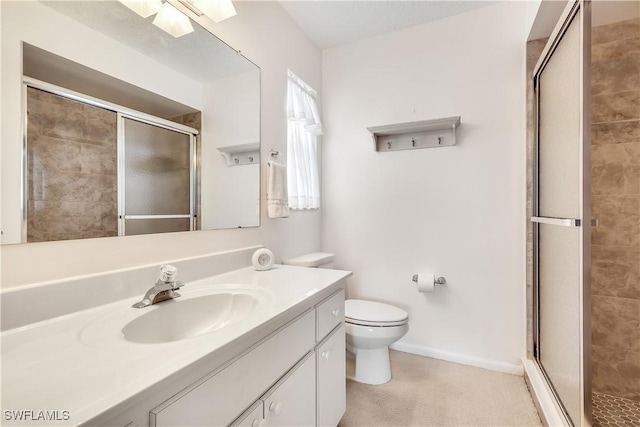 bathroom with vanity, a shower with door, and toilet