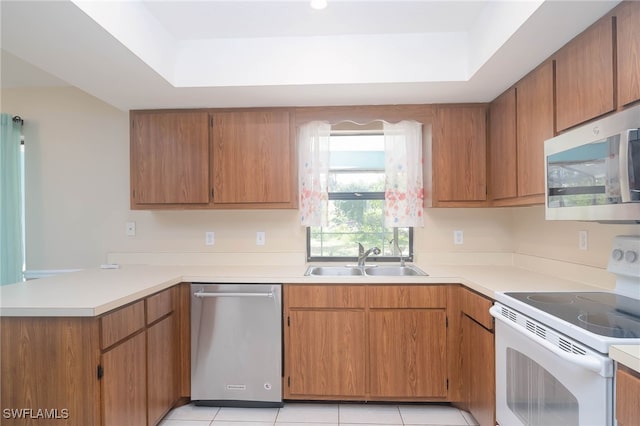 kitchen featuring sink, a raised ceiling, kitchen peninsula, light tile patterned floors, and appliances with stainless steel finishes