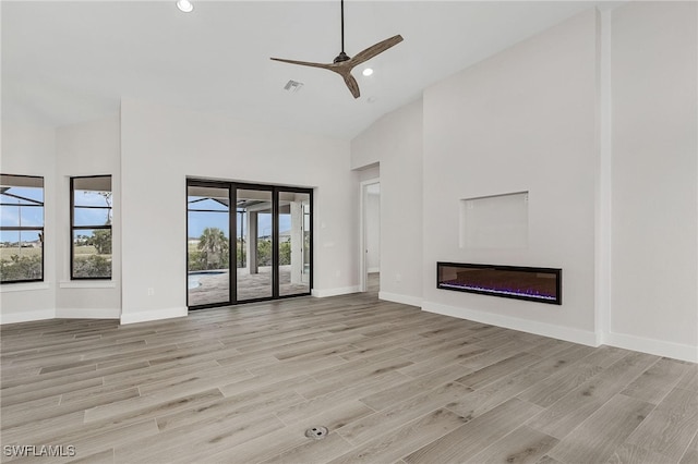 unfurnished living room featuring light hardwood / wood-style floors, high vaulted ceiling, ceiling fan, and a healthy amount of sunlight