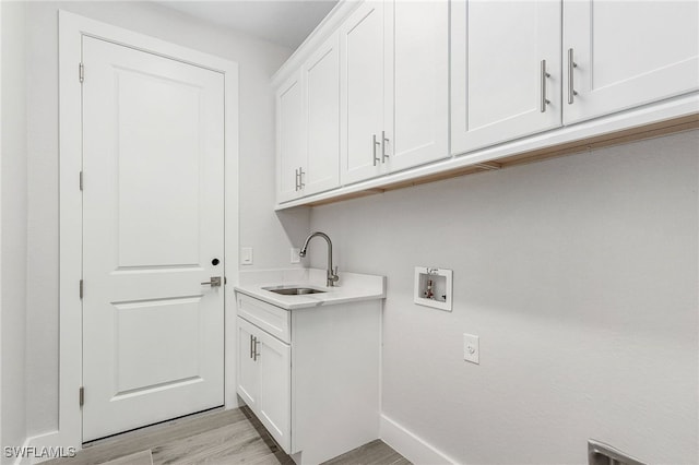 washroom with washer hookup, light hardwood / wood-style floors, cabinets, and sink