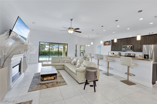 living room with light tile patterned floors, ceiling fan, and sink