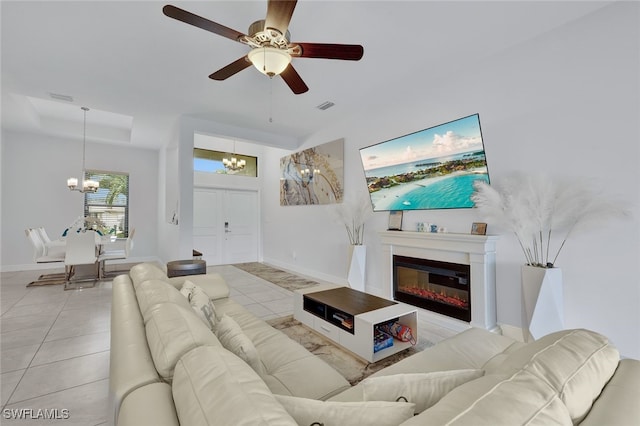 tiled living room featuring ceiling fan with notable chandelier