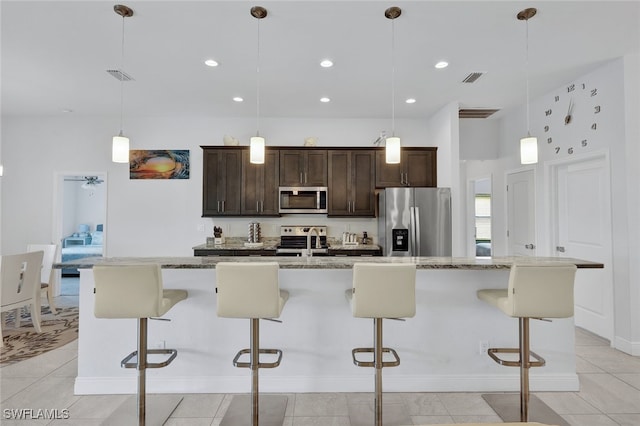 kitchen featuring a breakfast bar, hanging light fixtures, appliances with stainless steel finishes, and a kitchen island with sink