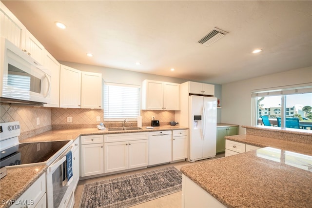 21671/21673 Indian Bayou Dr, Fort Myers Beach, FL 33931 - kitchen with white appliances, plenty of natural light, decorative backsplash, white cabinets, and recessed lighting
